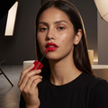 Maybelline Superstay Vinyl Ink Flüssiger Lippenstift, Model mit glänzend roten Lippen beim Auftragen