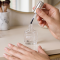 Maybelline Express Finish Nagellack transparent, Pinsel über dem offenen Flakon, Hände mit glänzenden Nägeln
