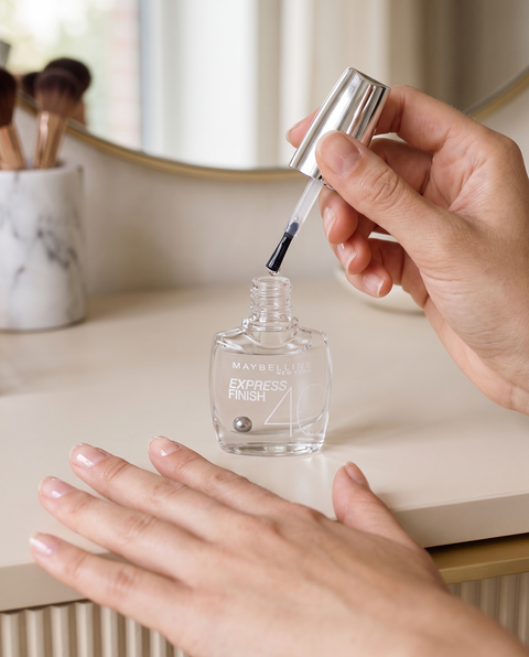 Maybelline Express Finish Nagellack transparent, Pinsel über dem offenen Flakon, Hände mit glänzenden Nägeln