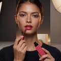 Model trägt Maybelline Superstay Vinyl Ink in glänzendem Pink und trägt den Lippenstift mit dem Applikator auf